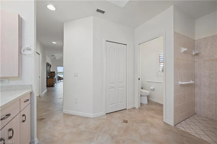 Bathroom featuring vanity, toilet, and a tile shower