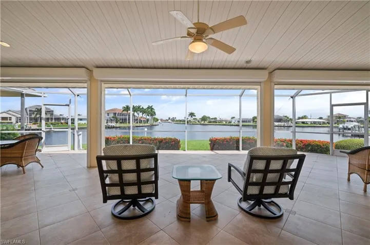 Sunroom / solarium featuring ceiling fan and a water view