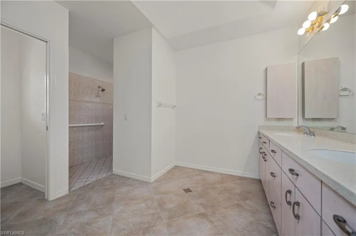 Bathroom featuring tile patterned flooring, a tile shower, and vanity