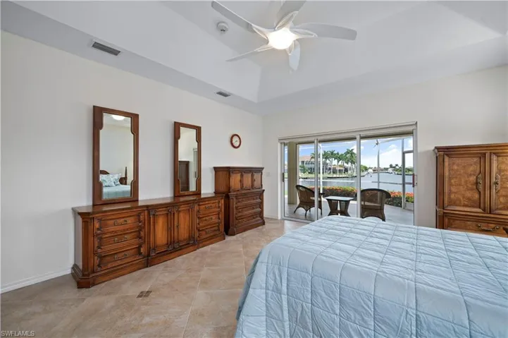 Bedroom featuring a raised ceiling, ceiling fan, and access to outside