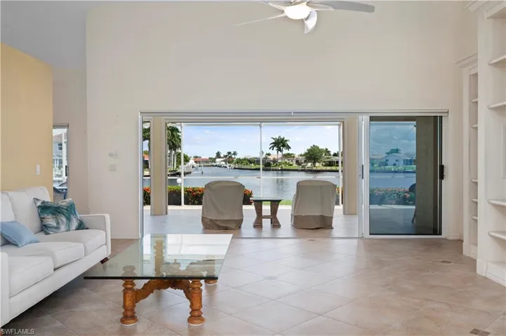Tiled living room with a towering ceiling, a water view, and ceiling fan