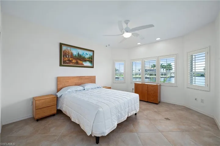 Bedroom with multiple windows, light tile patterned floors, and ceiling fan