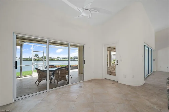 Spare room with a water view, light tile patterned floors, ceiling fan, and a wealth of natural light