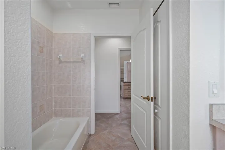 Bathroom with tiled shower / bath combo and tile patterned floors
