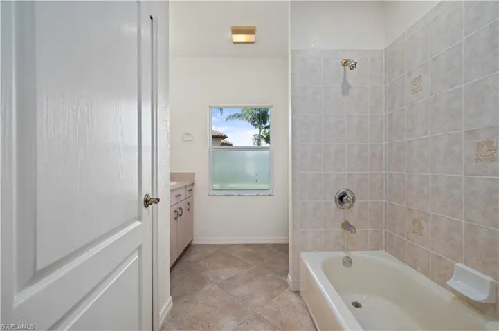 Bathroom featuring tile patterned floors, tiled shower / bath combo, and vanity