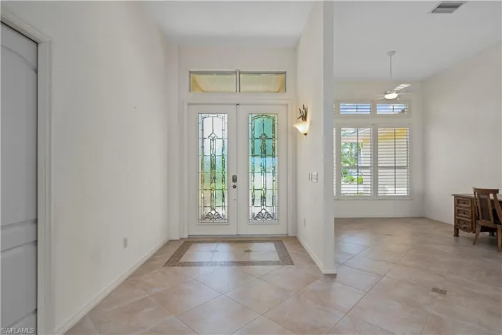 Tiled entrance foyer with ceiling fan and french doors
