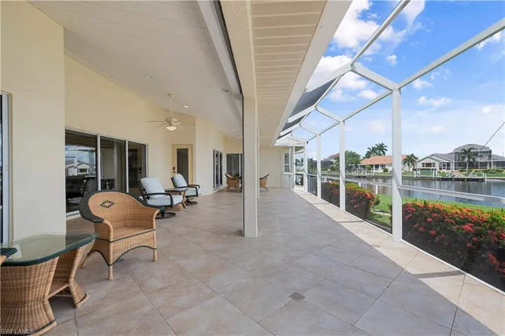 View of patio with a lanai, a water view, and ceiling fan