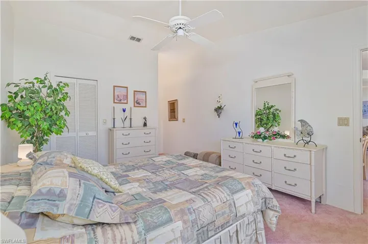 Bedroom featuring light colored carpet, visible vents, a closet, and a ceiling fan