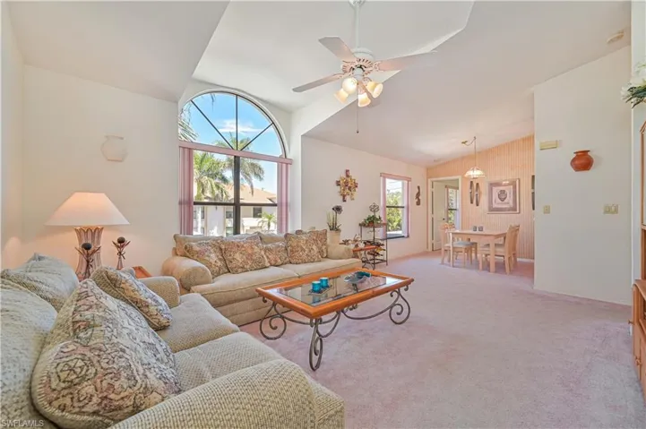 Carpeted living room featuring lofted ceiling and ceiling fan