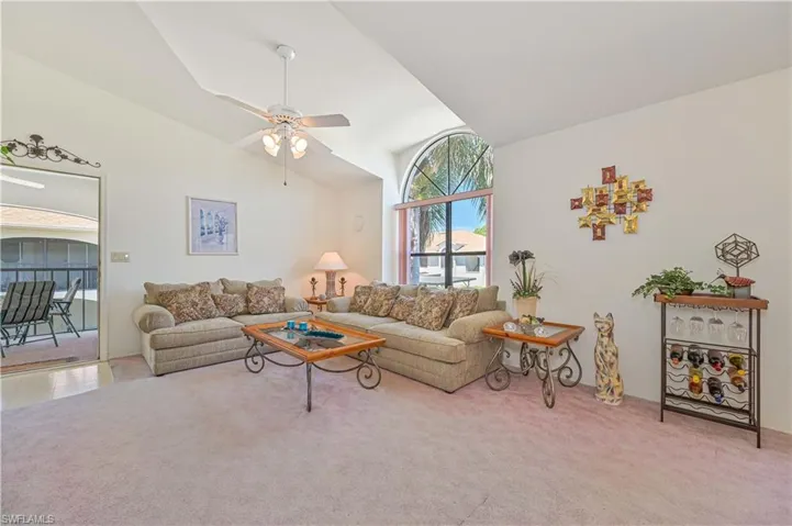 Living room with high vaulted ceiling, carpet floors, and a ceiling fan