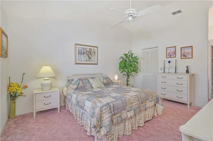 Bedroom featuring a closet, light carpet, lofted ceiling, visible vents, and ceiling fan