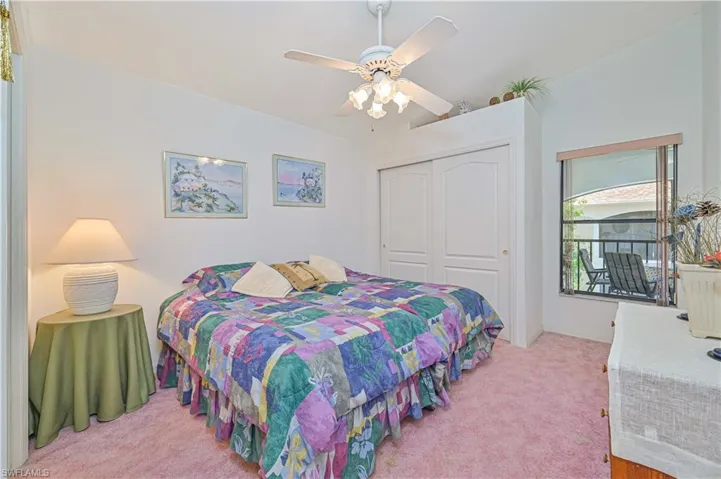 Bedroom featuring light carpet, lofted ceiling, a closet, and a ceiling fan
