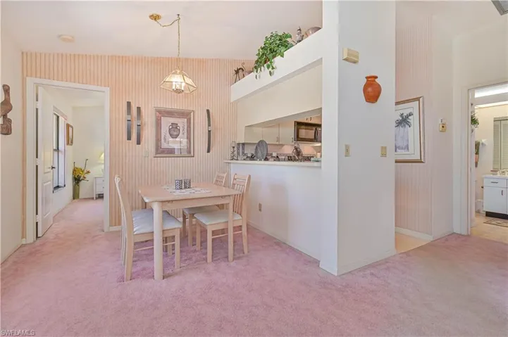 Carpeted dining room with baseboards and wallpapered walls