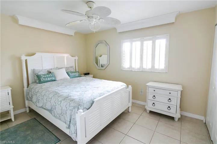 Bedroom featuring light tile patterned floors, a ceiling fan, and crown molding