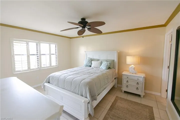 Bedroom with crown molding, light tile patterned flooring, and a ceiling fan