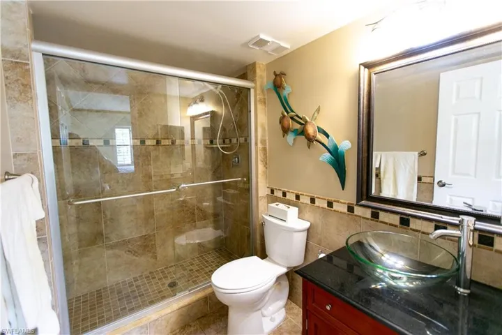 Full bath with tile walls, vanity, a stall shower, a wainscoted wall, and tile patterned flooring