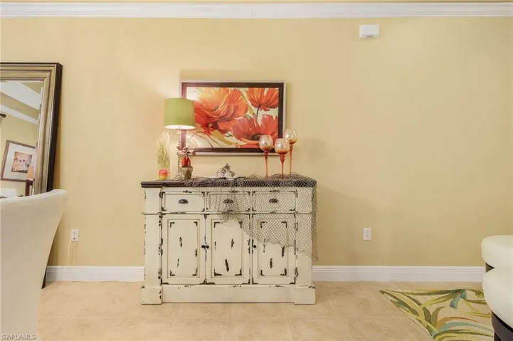 Living area with tile patterned floors, baseboards, and crown molding