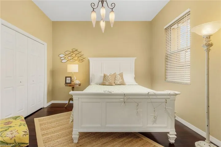 Bedroom featuring a closet, dark wood-style flooring, and baseboards