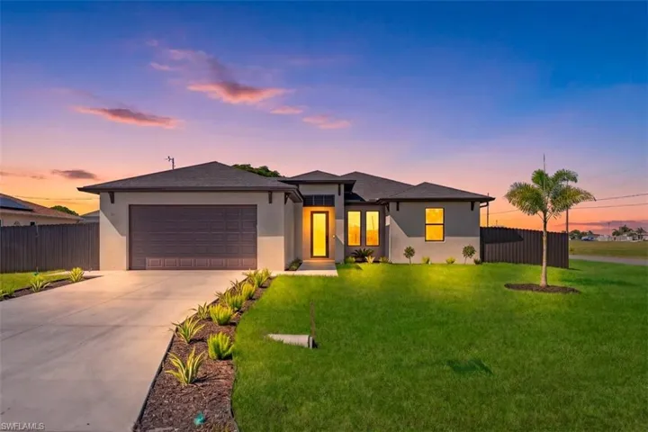 Single-story residence featuring a smooth stucco exterior, asphalt shingle roof, two-car garage, concrete driveway, and landscaped front yard with palm tree