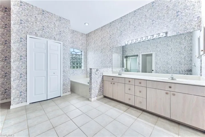 Bathroom with tile patterned floors, vanity, and tiled tub