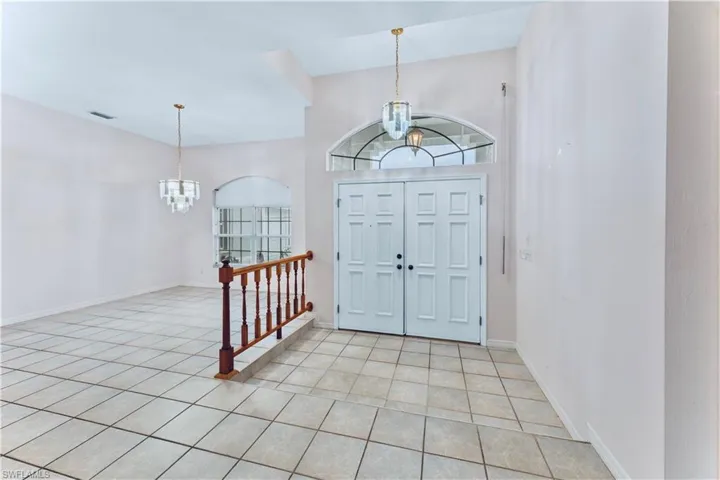 Foyer featuring light tile patterned floors and a notable chandelier