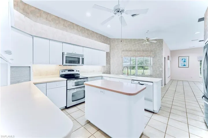 Kitchen featuring stainless steel appliances, a center island, sink, and white cabinets