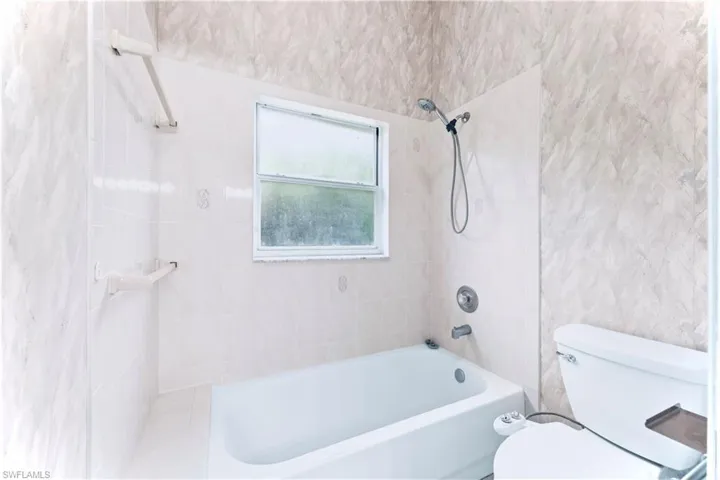 Bathroom featuring tiled shower / bath combo and toilet