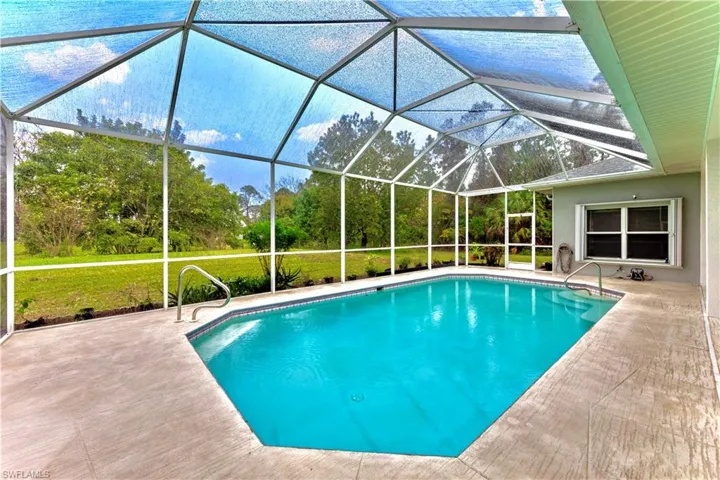View of pool with a patio area and glass enclosure