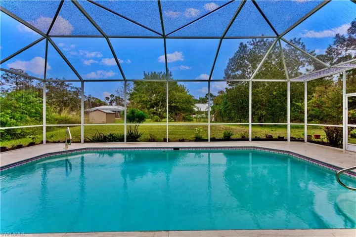 View of swimming pool featuring a lanai, a lawn, and a patio