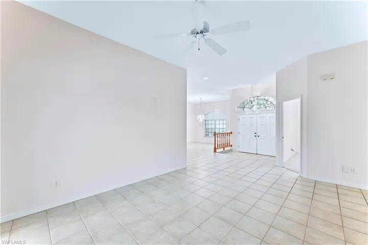 Tiled spare room with ceiling fan with notable chandelier