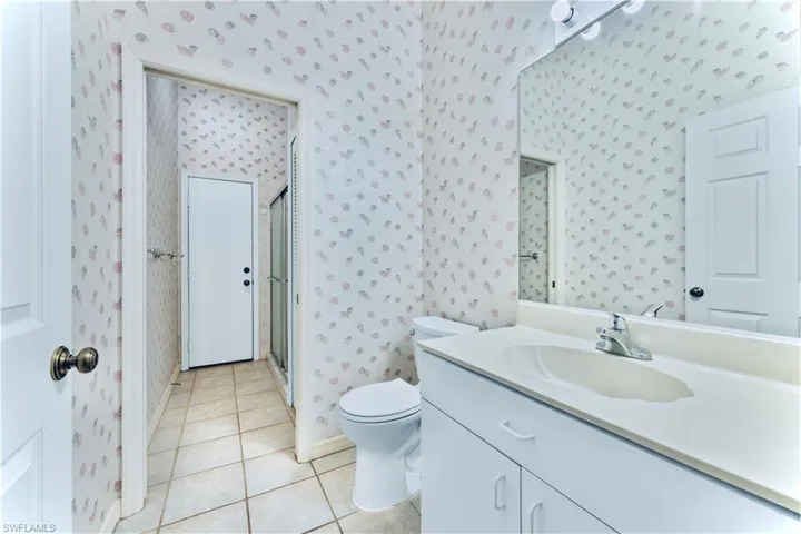 Bathroom featuring vanity, an enclosed shower, tile patterned floors, and toilet