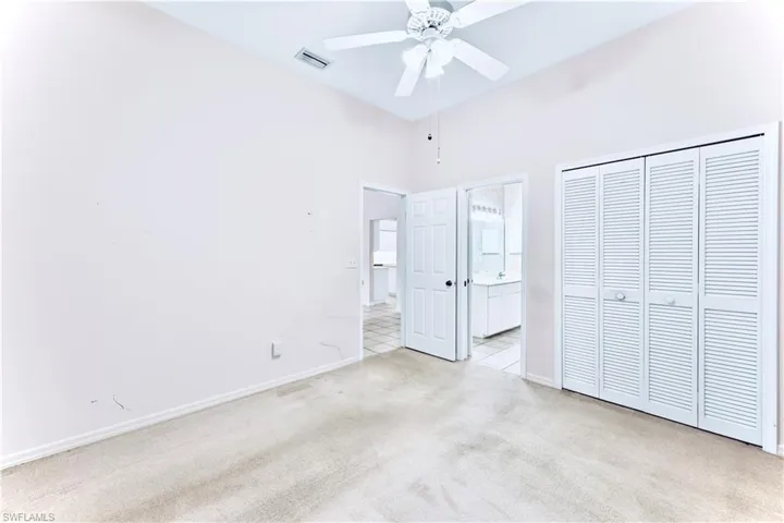 Unfurnished bedroom with ceiling fan, light colored carpet, a closet, and a towering ceiling
