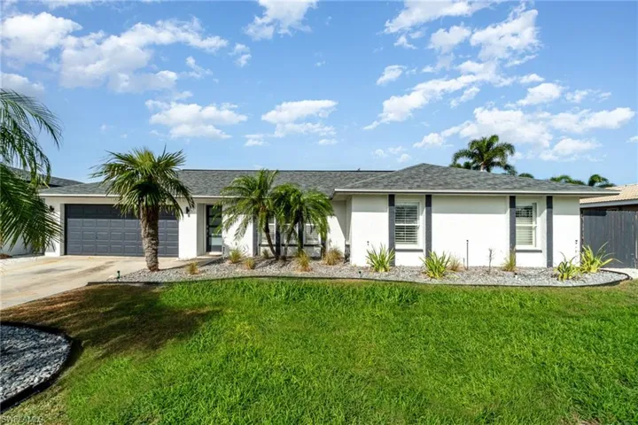 Ranch-style house with stucco siding, a front yard, and driveway
