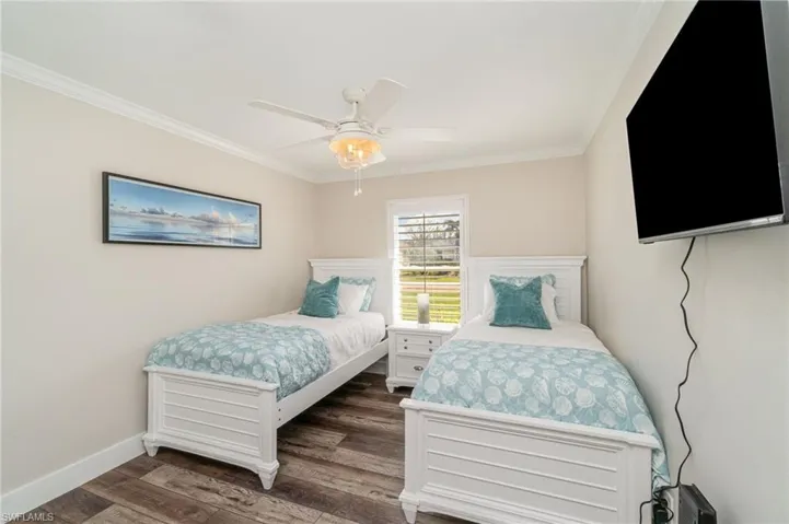 Bedroom with crown molding, dark wood-style flooring, and ceiling fan
