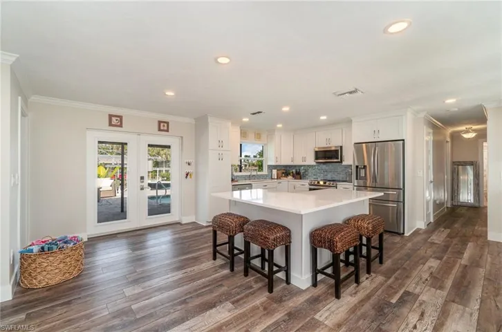 Kitchen featuring stainless steel appliances, white cabinets, a breakfast bar area, crown molding, and french doors