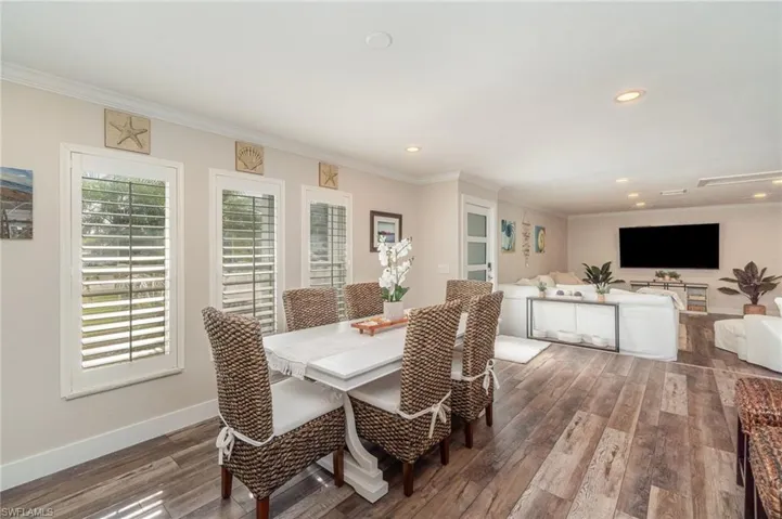 Dining room with crown molding, dark wood finished floors, and recessed lighting
