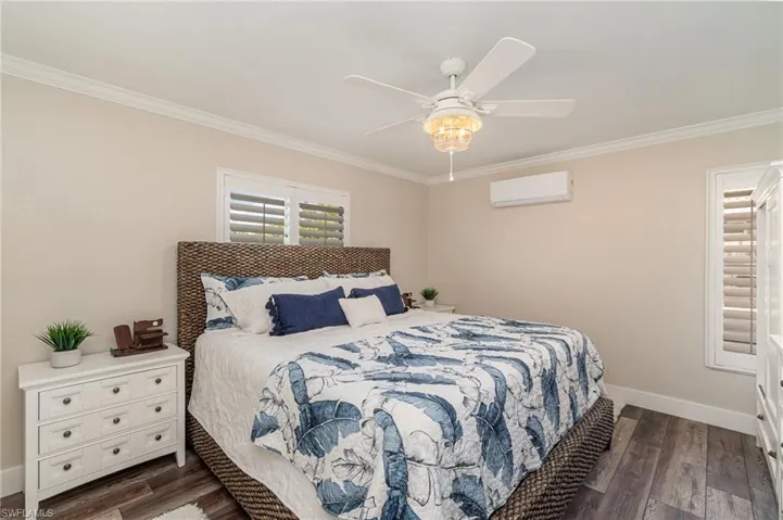 Bedroom featuring ornamental molding, dark wood finished floors, ceiling fan, and a wall mounted AC