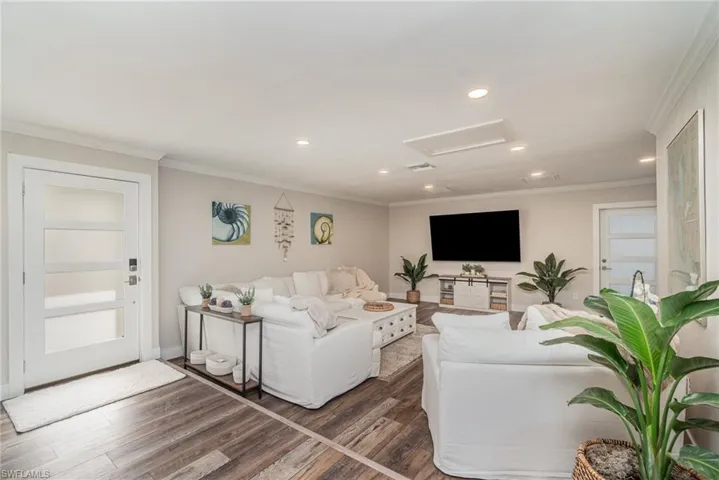 Living area with attic access, crown molding, wood finished floors, and recessed lighting