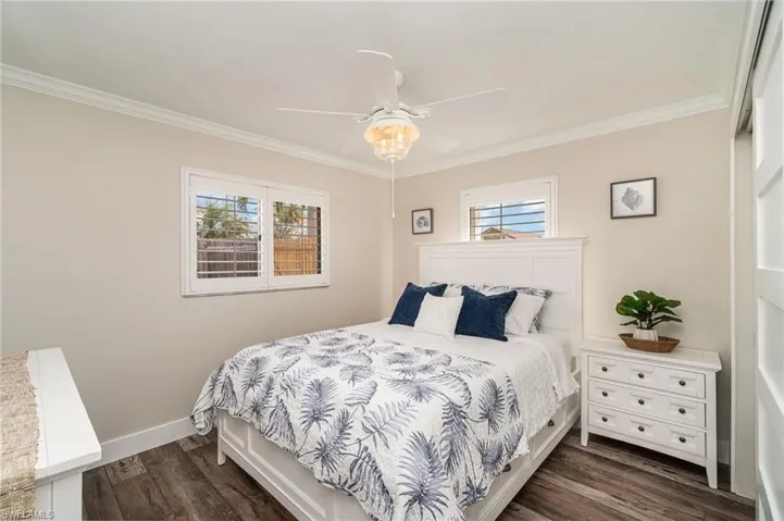 Bedroom featuring multiple windows, crown molding, dark wood-style flooring, and ceiling fan