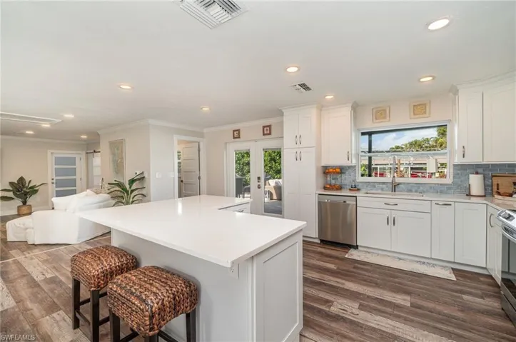 Kitchen featuring a kitchen breakfast bar, white cabinets, recessed lighting, tasteful backsplash, and open floor plan