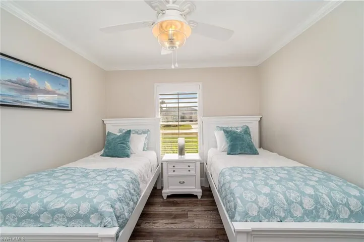 Bedroom with ornamental molding, dark wood-type flooring, and ceiling fan