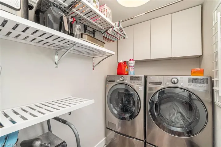 Washroom featuring independent washer and dryer and cabinet space