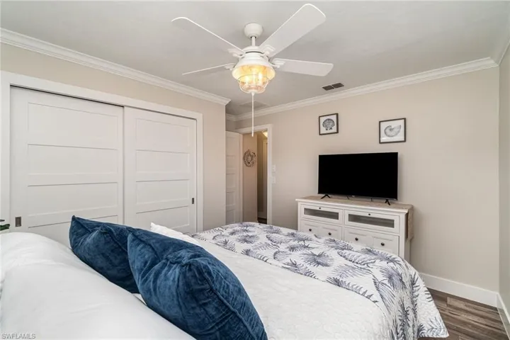 Bedroom featuring ornamental molding, dark wood finished floors, ceiling fan, and a closet
