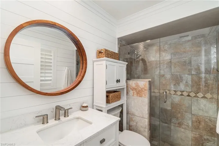 Bathroom with vanity, a stall shower, crown molding, and wood walls