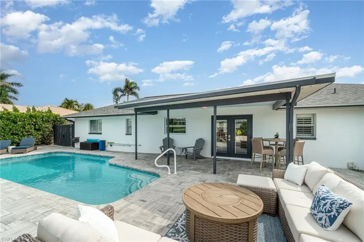 Rear view of property featuring an outdoor living space, french doors, roof with shingles, stucco siding, and a patio area