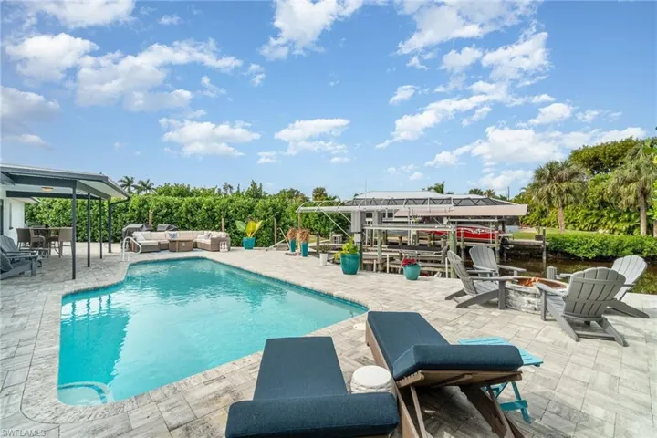 Outdoor pool featuring an outdoor living space with a fire pit, a patio area, and boat lift