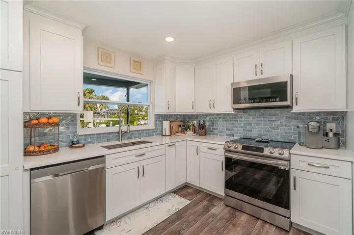 Kitchen with stainless steel appliances, white cabinets, dark wood finished floors, backsplash, and recessed lighting