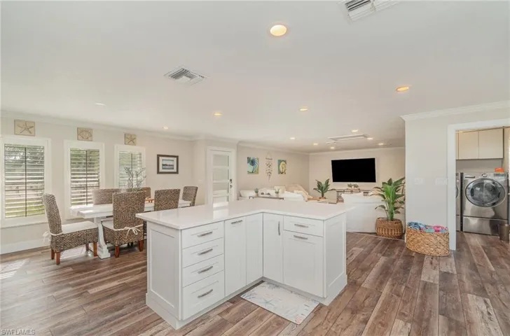 Kitchen with ornamental molding, recessed lighting, white cabinets, dark wood-type flooring, and a center island