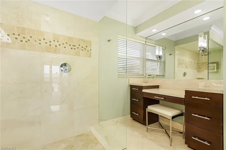 Bathroom featuring vanity, a tile shower, and crown molding