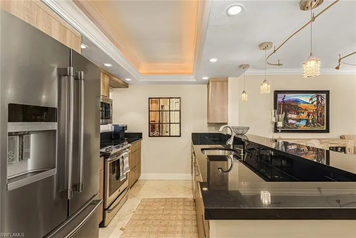 Kitchen featuring ornamental molding, appliances with stainless steel finishes, light brown cabinets, pendant lighting, and sink